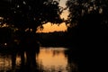 Evening view of the lake, through the lake you can see the silhouettes of trees and a small chapel.