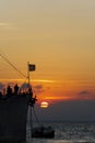 Old moored Greek warship with flag against sea level sunset