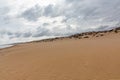 Evening view on small sand dune with green grass. Sandy beach at sea coast. Blue sky with white clouds. Sunset time