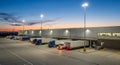 Evening View of Trucks Docked at a Large Commercial Warehouse Loading Bay with Illuminated Structures and Twilight Sky Royalty Free Stock Photo