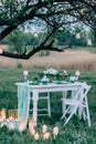 Evening wedding ceremony with a rug and lot of vintage lamps and candles on big tree. Rustic style