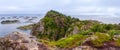 Wide panoramic view from top of cliff range over the ocean and on blue panorama of mountains and Reine in Lofoten islands, Norway Royalty Free Stock Photo