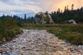 Evening wooded mountain valley with blurred river water and a scenic cliff in the distance