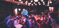 Event hall: Close up of microphone stand, seats with audience in the blurry background