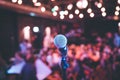 Event hall: Close up of microphone stand, seats with audience in the blurry background Royalty Free Stock Photo