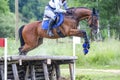 Eventing: equestrian rider jumping over an a log fence obstacle