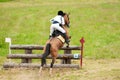 Eventing: equestrian rider jumping over an a log fence obstacle