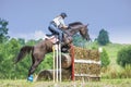 Eventing: equestrian rider jumping over an a brance fence obstacle