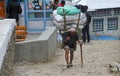 EVEREST CAMP, NATIONAL PARK, NEPAL - APRIL 15. 2017. The old sherpa porter carrying heavy sacks Royalty Free Stock Photo