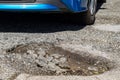 Car going over a pot hole in pot hole damaged road