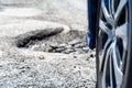 Car going over a pot hole in pot hole damaged road