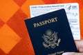 Hand Holding an American Passport and Covid Vaccination Card