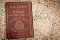 A studio shot of an antique Paris Tour Book with Included Map in Background