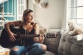 Every artist appreciates an attentive audience. a young woman playing a guitar on a relaxing day at home.