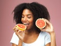 Every bite goes towards better health. Studio shot of an attractive young woman eating grapefruit against a pink Royalty Free Stock Photo