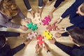 Colored puzzle pieces that business people connect together during team building.