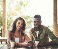 Every couple has their favourite coffeeshop. a woman using her cellphone while sitting in a cafe with her boyfriend.