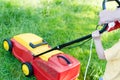 Every little help counts: image of electric grass trimming or lawn mover machine operating or pushing by small boy or girl Royalty Free Stock Photo