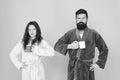 Every morning begins with coffee. Couple in bathrobes with mugs. Breakfast concept. Man with beard and sleepy woman