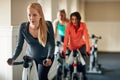 Every spinning class brings her closer to her fitness goals. a young woman working out with an exercise bike in a Royalty Free Stock Photo