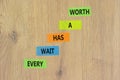 Every wait has a worth symbol. Concept words Every wait has a worth on colored paper. Beautiful wooden table wooden background. Royalty Free Stock Photo