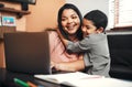 Every working mom is a superwoman. a mother using a laptop while her son is hugging her at home.