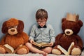 Everybody needs a cool study buddy. Studio shot of a smart little boy reading a book next to his teddy bears against a Royalty Free Stock Photo