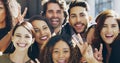 Everybody wants a peace of the pie. a group of businesspeople giving the peace sign while standing in their office.