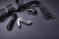 Everyday carry EDC items for men in black color - tactical belt, flashlight, watch and silver multi tool.