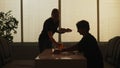 Silhouette of man sitting at the bistro food bar, female waitress brings him order juice and pizza on a plate. Royalty Free Stock Photo