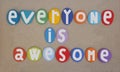 Everyone is awesome, creative slogan composed with multi colored stone letters over beach sand Royalty Free Stock Photo