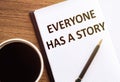 EVERYONE HAS A STORY - text on notepad on wooden desk Royalty Free Stock Photo
