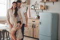 Everyone hugs each other. Cute family photo of pregnant mother, father and their daughter. Standing at the kitchen Royalty Free Stock Photo