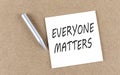 EVERYONE MATTERS text on sticky note on cork board with pencil