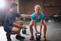 Everyone needs a helping hand once in awhile. a trainer helping a young woman lifting kettlebells in a gym. Royalty Free Stock Photo