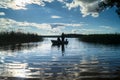 Silhouette of fishers in the rowing boat, floating towards the lakeshore under the blinding sunlight. Seliger, Russia.