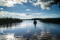 Silhouette of fishers in the rowing boat, floating towards the lakeshore under the blinding sunlight. Seliger, Russia.