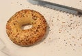 Everything Bagel With Knife and Scattered Seeds on a Table