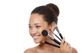 Everything she needs for a flawless face. Beauty portrait of a young woman holding up make-up brushes.