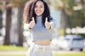 Everything is perfectly fine over here. an attractive young woman standing alone outside and showing a thumbs up.