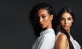 Everything about them is stunning. Portrait of two attractive young women posing back to back against a dark background