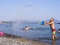 Evia Island, Greece. August 2019: Family: father, daughter and son play and pour water on the beach on a Greek island on a summer