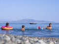 Evia Island, Greece. August 2019: Family: father, daughter and son playing ball  with water on the beach on a Greek island on a su Royalty Free Stock Photo