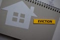 Eviction write on sticky note and house made from paper isolated on Office Desk