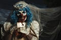 Evil clown in bride dress strangling a teddy bear