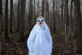 Evil clown in a dark forest in a white veil Royalty Free Stock Photo