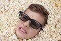 Evil ferocious young boy in stereo glasses looking out of popcorn