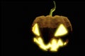 Evil grin and glowing yellow eyes illuminated by candle burning inside a Pumpkin in Halloween mystery and nightmare