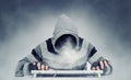 Evil hacker man anonymous in hoodie behind the keyboard, smoke instead of face.