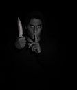 Evil man gesturing silence while holding a knife Royalty Free Stock Photo